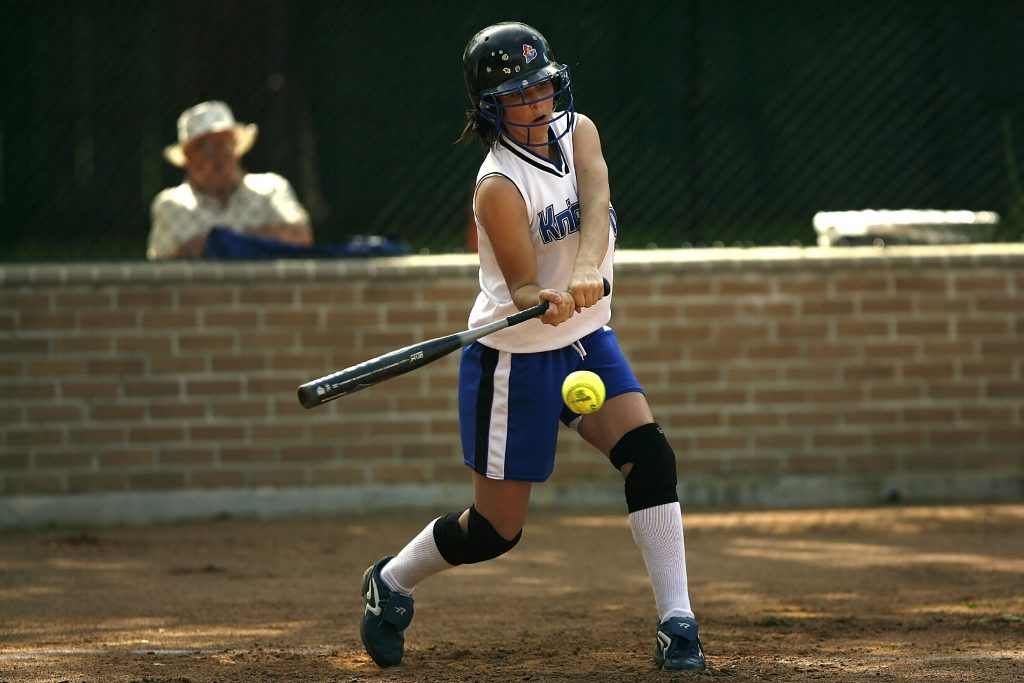 A woman playing baseball with a black baseball bat