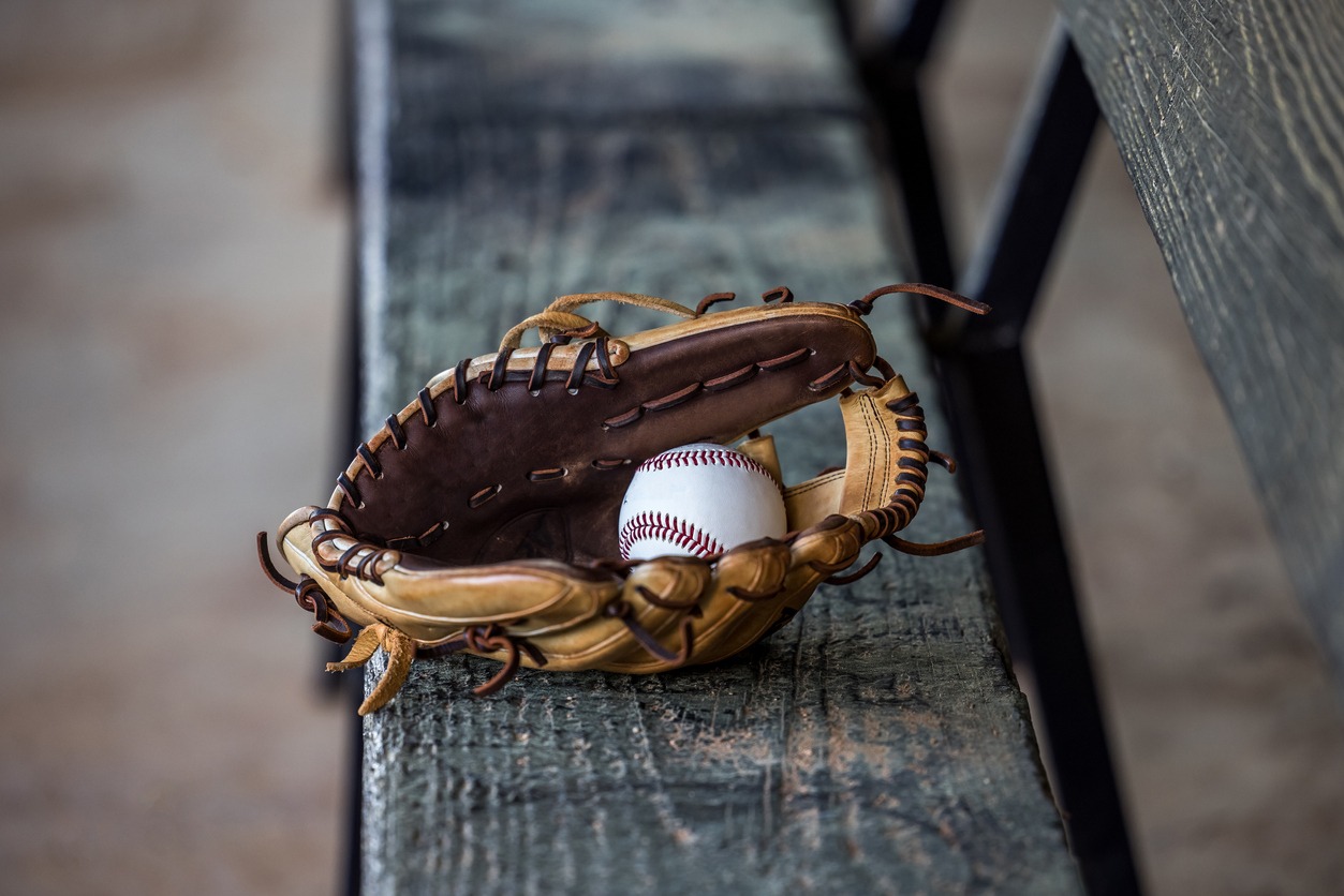 A baseball glove with a ball on a bench