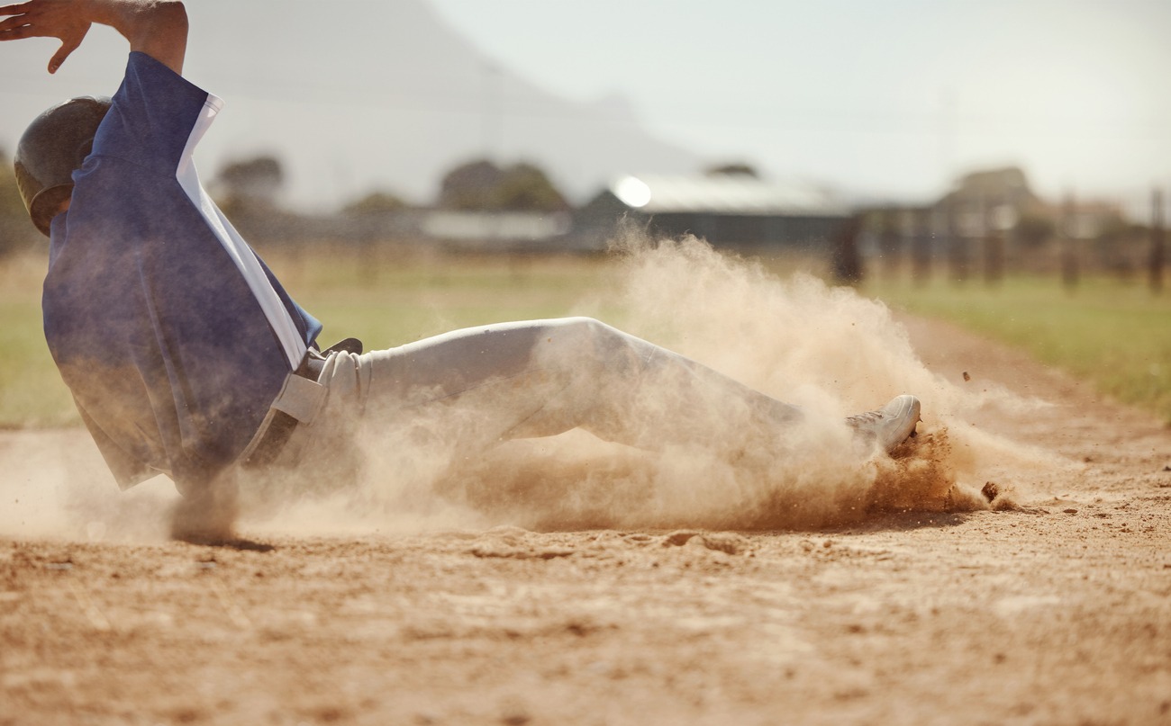 A baseball player running and sliding for home plate